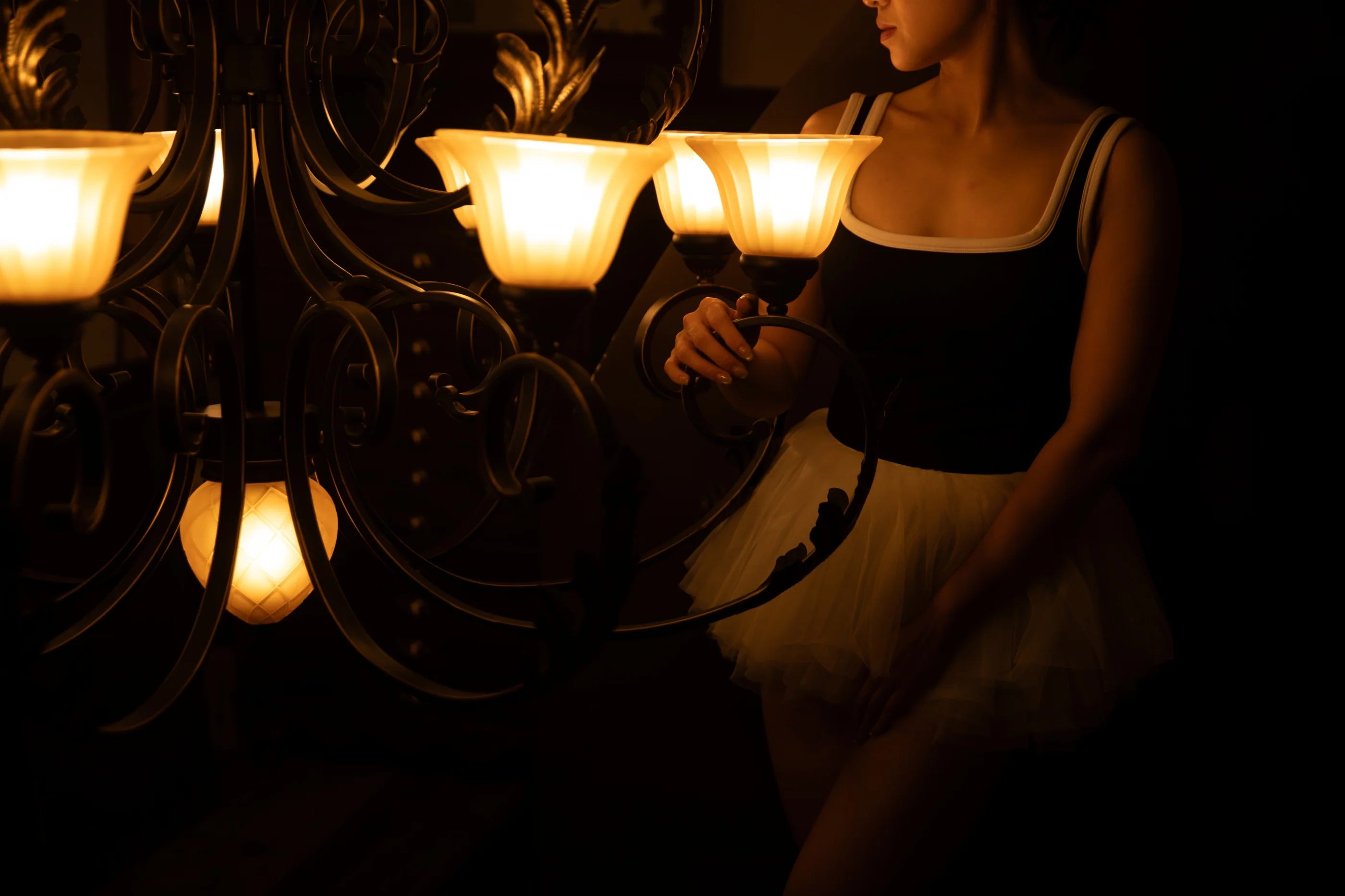 SHEVEREIGN woman beside warm chandelier light, symbolizing confidence and guidance in women’s pleasure journey