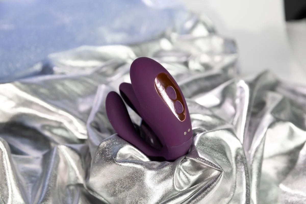 SHEVEREIGN Whisper Wear wearable vibrator showcased on silver satin fabric, highlighting its elegant shape and smooth body safe design