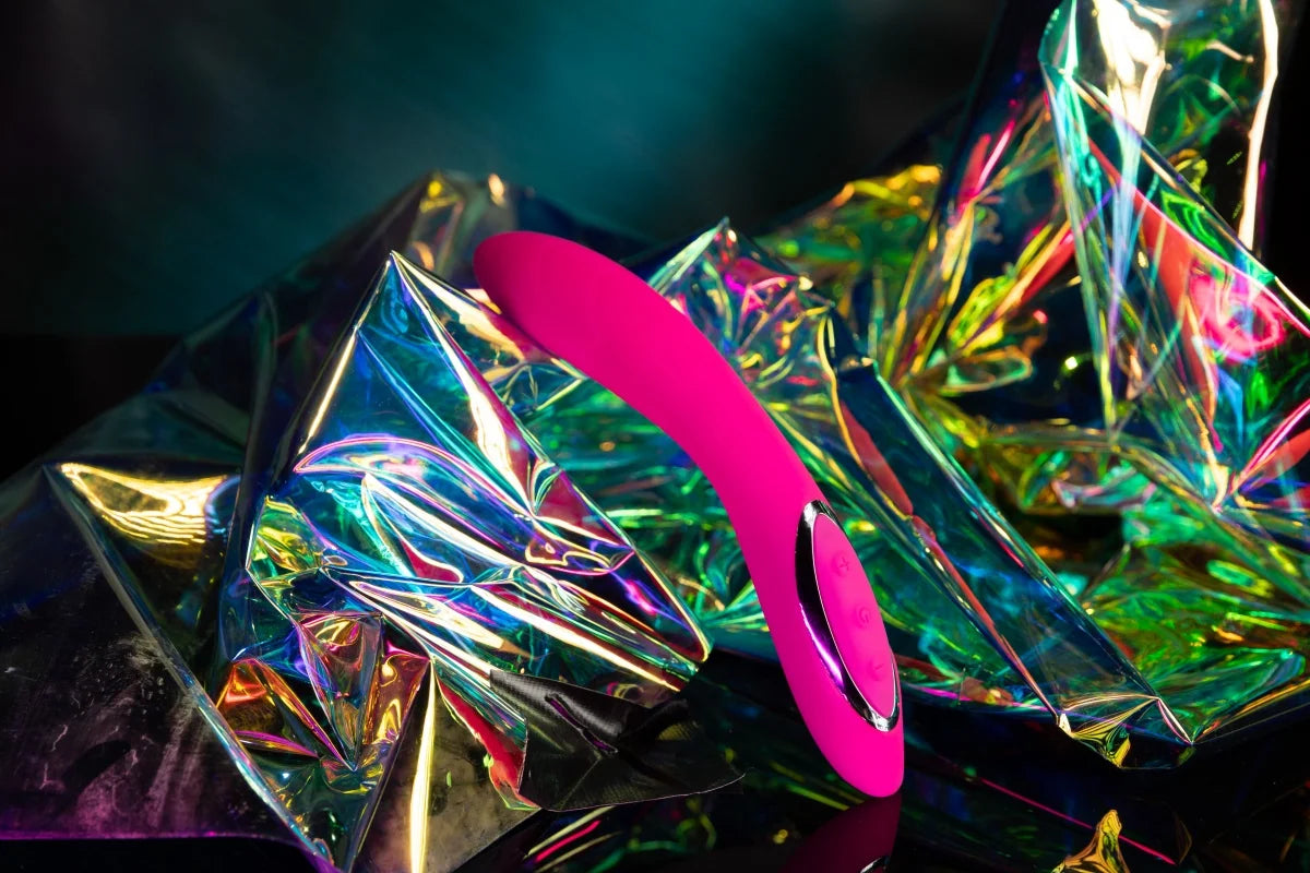 SHEVEREIGN Fuchsia Wave G spot vibrator showcased against holographic textures, highlighting its curved design and vibrant feminine energy